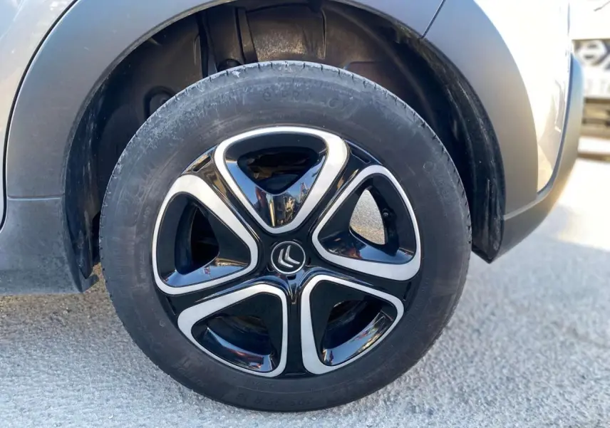 Gros plan sur la roue avant gauche d'une Citroën C3 gris Artense avec jante noire et argentée au design moderne.