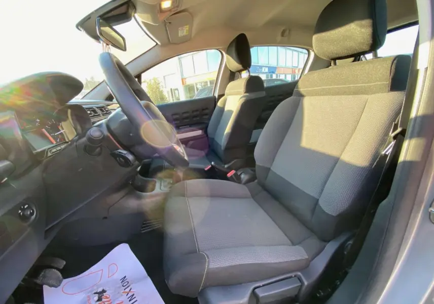 Vue intérieure côté conducteur de la Citroën C3 2022 gris Artense, sièges tissu bicolore et tableau de bord moderne.