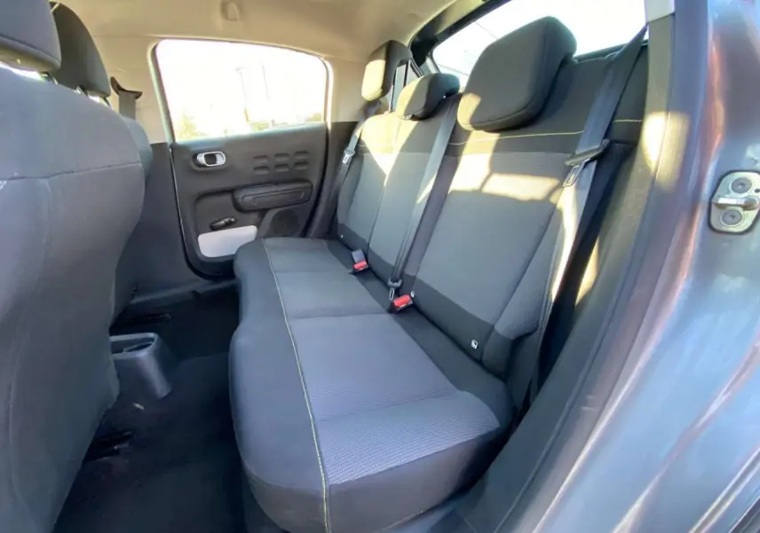 Vue intérieure de la banquette arrière de la Citroën C3 gris Artense, avec ceintures et portes ouvertes côté droit.