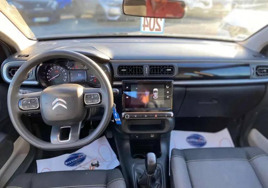 Vue intérieure avant du tableau de bord et volant de la Citroën C3 gris Artense 2022 avec écran tactile et boîte manuelle.