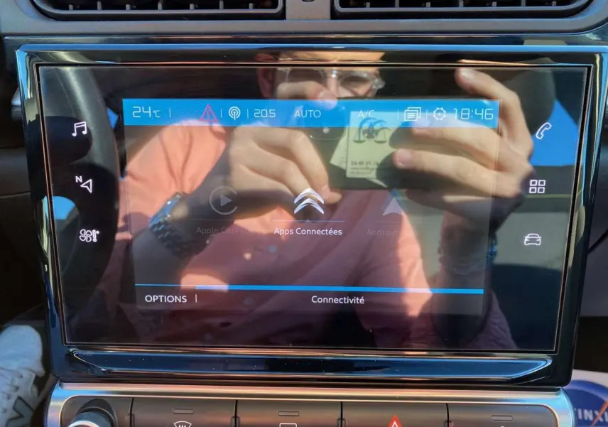 Écran tactile central de la Citroën C3 Gris Artense 2022 affichant les options connectées avec reflets du conducteur.