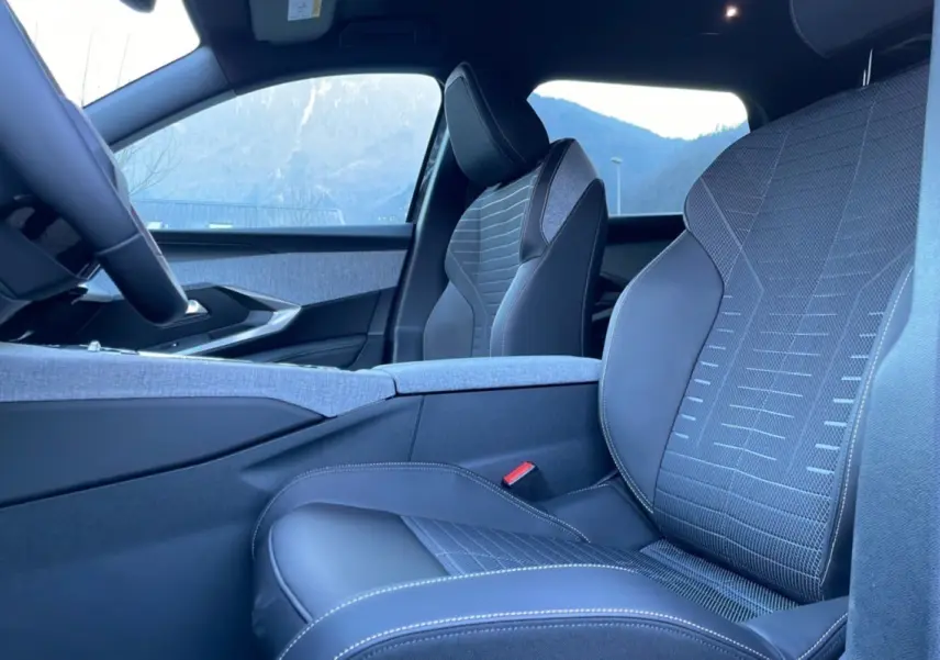Intérieur du Peugeot 5008 Hybrid 145 Allure Plus 2025, sièges avant en tissu et cuir gris avec surpiqûres blanches.