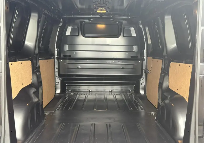 Vue intérieure arrière du Citroën Jumpy gris Titane, montrant l'espace de chargement métallique avec panneaux latéraux en bois clair.
