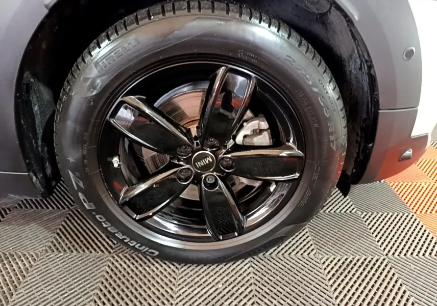 Gros plan sur la roue avant droite d'une MINI Countryman gris clair avec jante noire brillante à cinq branches.