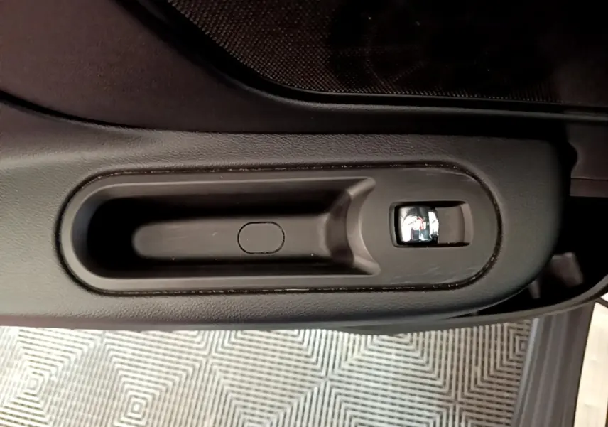 Poignée intérieure de porte noire avec bouton de verrouillage, vue en plongée dans une MINI Countryman gris clair.
