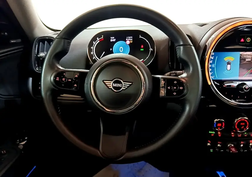 Vue intérieure centrée sur le volant cuir MINI avec tableau de bord digital et écran tactile central éclairé.