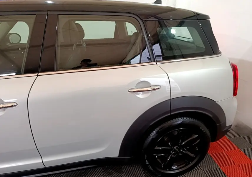 Vue latérale droite d'un MINI Countryman gris clair avec toit noir et jantes noires brillantes.