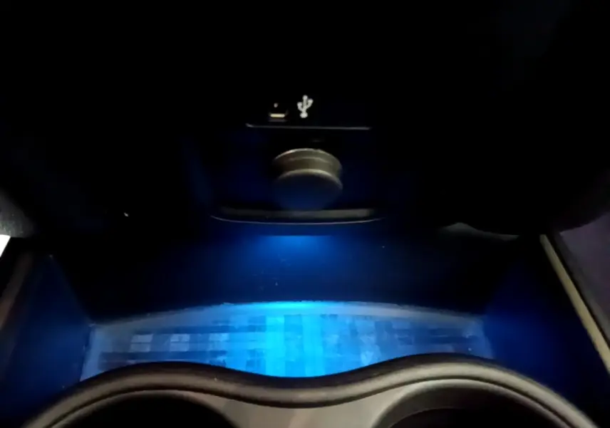 Gros plan sur la zone de recharge par induction avec éclairage d'ambiance bleu dans le coffre avant du MINI Countryman gris clair.