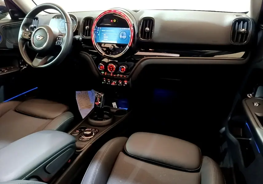 Intérieur avant du MINI Countryman Cooper gris, vue côté conducteur sur tableau de bord et éclairage d’ambiance bleu.