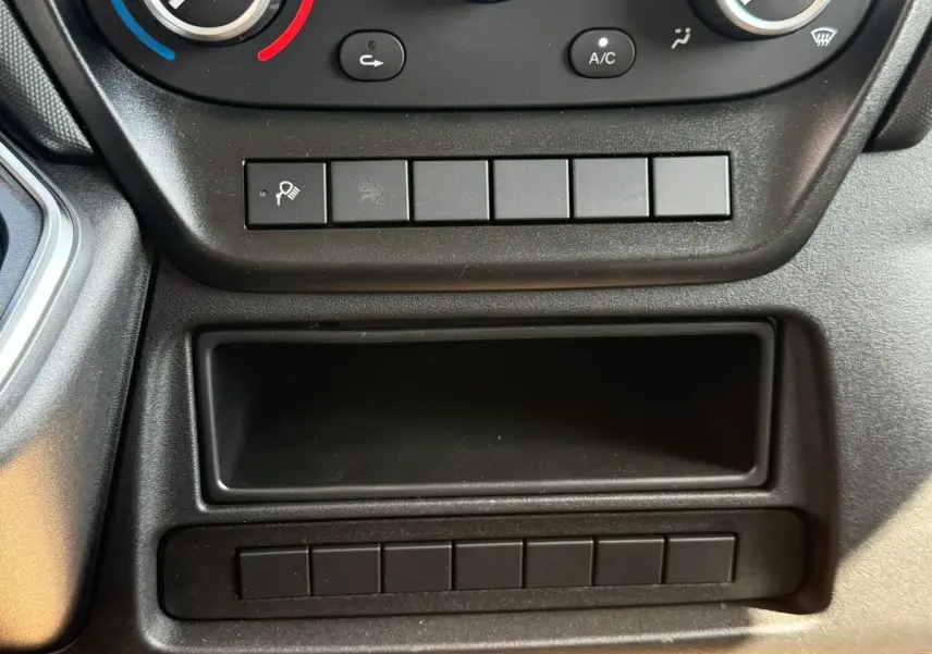 Détail de la console centrale noire de l'Iveco Daily 35S18 2026 avec boutons de commande et rangement vide.