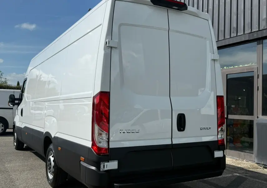 Vue 3/4 arrière droite d’un utilitaire Iveco Daily blanc avec portes arrière fermées et feux rouges visibles.