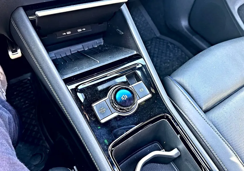 Vue rapprochée de la console centrale noire brillante du Volkswagen Tiguan 2024 avec accoudoir et siège cuir gris.
