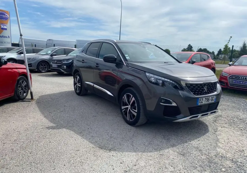 Peugeot 3008 gris platinium en 3/4 avant droit, avec barres de toit aluminium et projecteurs LED visibles.