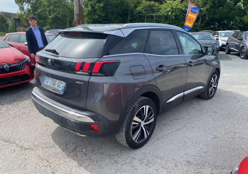 Peugeot 3008 gris platinium vue 3/4 arrière droit, avec barres de toit aluminium et feux LED distinctifs.