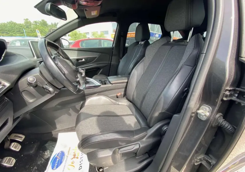 Vue intérieure côté conducteur du Peugeot 3008 gris platinium de 2018, sièges en tissu et cuir avec pédalier aluminium visible.
