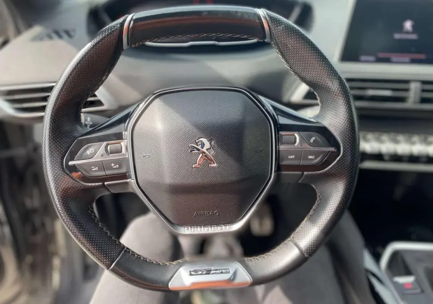 Vue rapprochée du volant cuir perforé du Peugeot 3008 GT Line 2018 avec commandes intégrées et logo lion central.