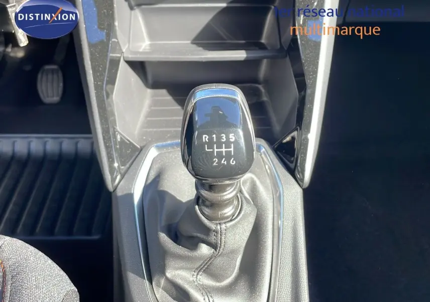 Le levier de vitesse manuel noir de la Peugeot 2008 blanc Okenite, vu en gros plan depuis l'intérieur.