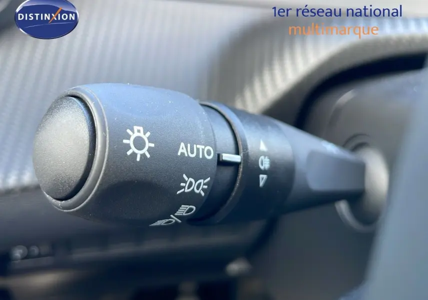 Gros plan sur la commande des phares automatiques dans l’habitacle d’une Peugeot 2008 blanche Okenite Metal 2025.