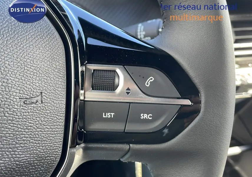 Gros plan sur les commandes gauche du volant en cuir noir du Peugeot 2008 blanc Okenite Metal 2025.