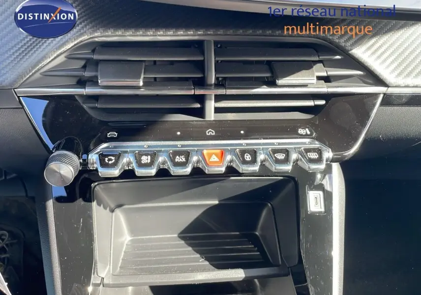 Vue rapprochée de la console centrale noire brillante du Peugeot 2008 blanc Okenite, avec commandes tactiles et aérateurs.