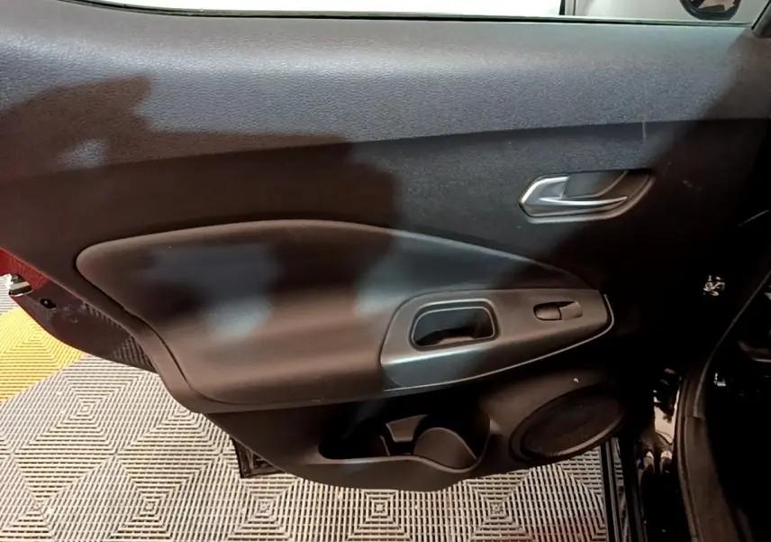 Vue intérieure du panneau de porte côté droit noir du Nissan Juke Hybrid 143 Business+ avec poignée et commande de fenêtre.