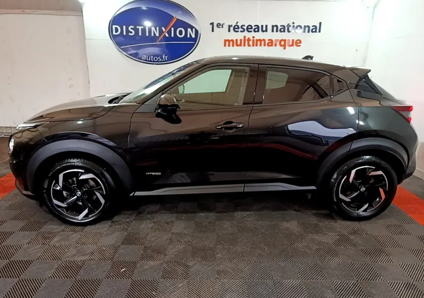 Profil droit d'un Nissan Juke Hybrid 143 Business+ noir, avec jantes noires et logo Hybrid visible sur la porte.