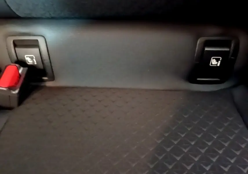Détail de la banquette arrière noire du Nissan Juke Hybrid 2022 avec fixation Isofix et boucle de ceinture rouge.