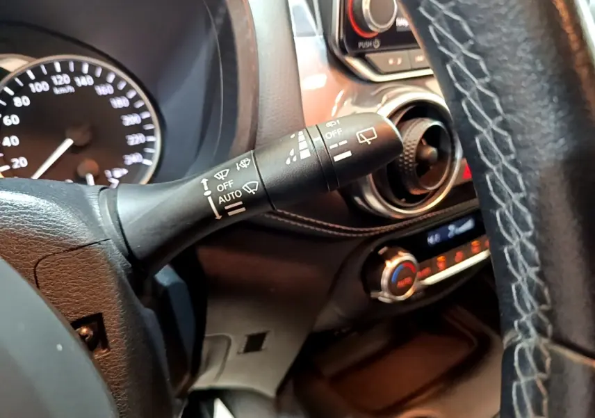 Gros plan intérieur sur le commodo d’essuie-glace et partie du tableau de bord du Nissan Juke Hybrid noir, côté conducteur.