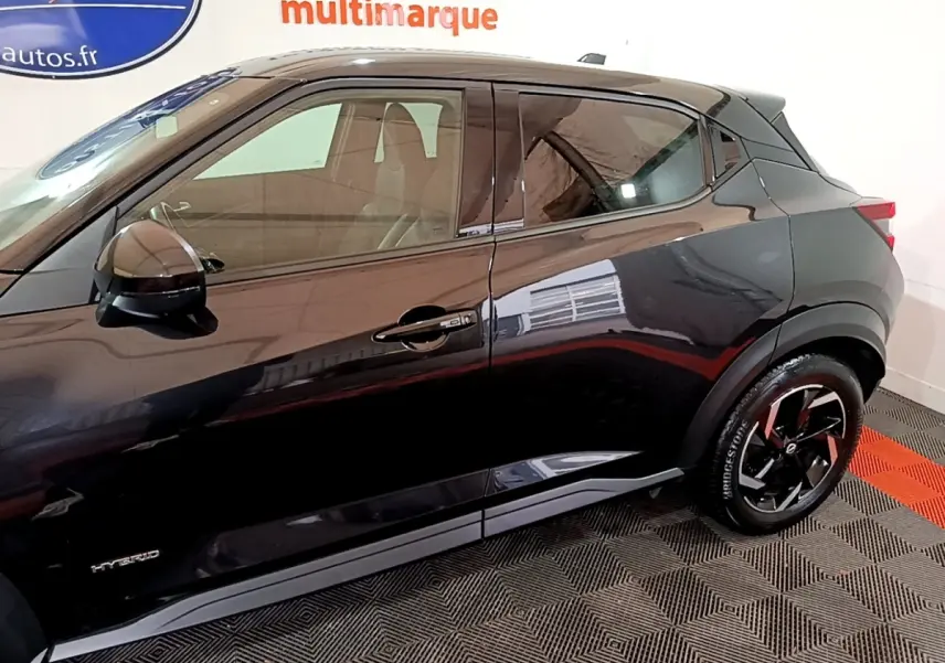 Vue de profil côté droit d'un Nissan Juke Hybrid 143 Business+ noir, mettant en valeur les jantes noires et le badge Hybrid.