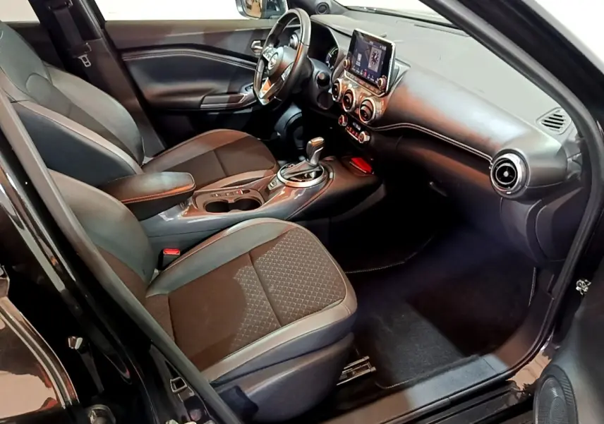 Intérieur côté conducteur du Nissan Juke Hybrid 2022 noir, avec tableau de bord moderne et écran tactile central.
