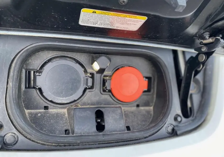Gros plan sur la trappe de recharge électrique ouverte d'une Nissan Leaf 40 N-Connecta blanche, montrant les prises de charge.