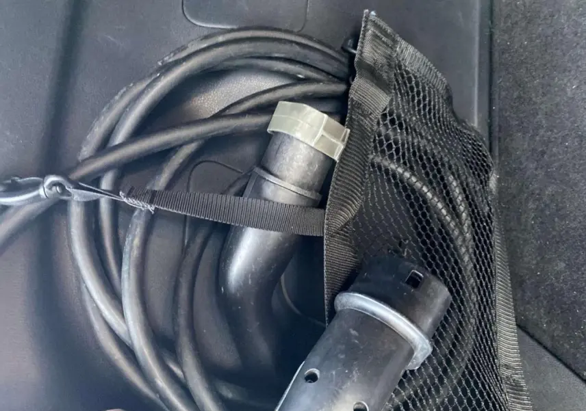 Câble de recharge électrique noir enroulé dans le coffre d'une Nissan Leaf blanche, version 40 N-Connecta.