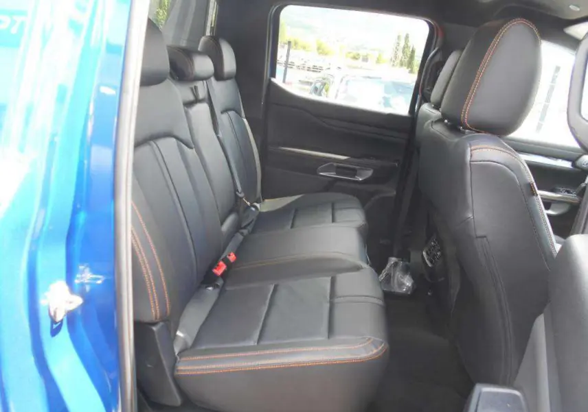 Vue intérieure côté gauche des sièges arrière en cuir noir avec surpiqûres orange du Ford Ranger Bleu Lightning 2025 Wildtrak Plus.