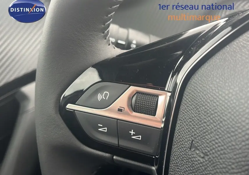 Gros plan sur les commandes au volant noir brillant du Peugeot 2008 blanc Okenite Metal, version 2025.