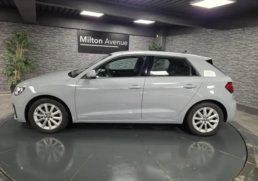 Profil côté gauche d'une Audi A1 Sportback gris Manhattan avec jantes aluminium 16 pouces en showroom.