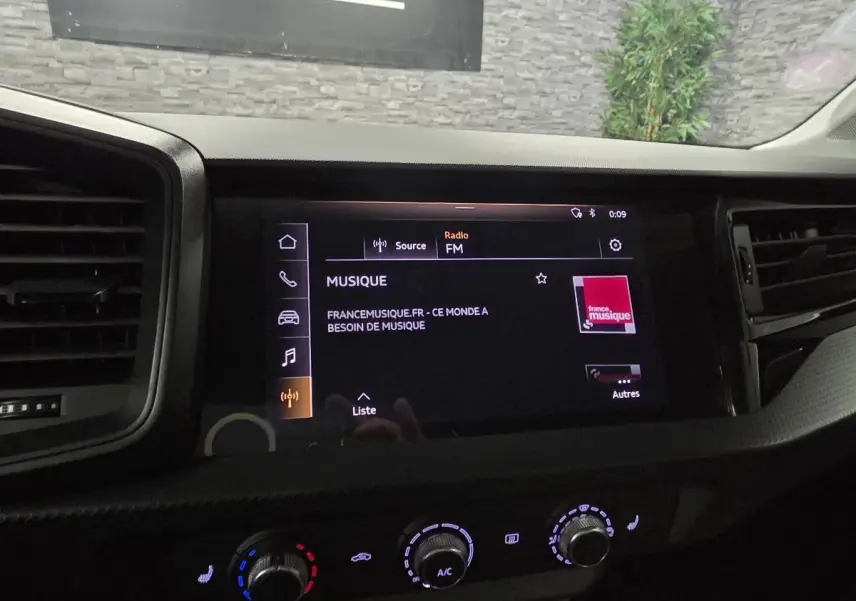 Tableau de bord de l'Audi A1 Sportback 2020 avec écran tactile MMI affichant la radio FM et commandes de climatisation.
