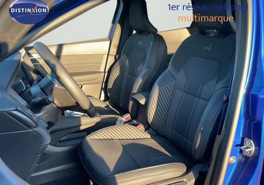 Intérieur avant du Renault Captur E-Tech hybride 2025, sièges noirs avec surpiqûres et logo Alpine, porte ouverte bleu Iron Metal.