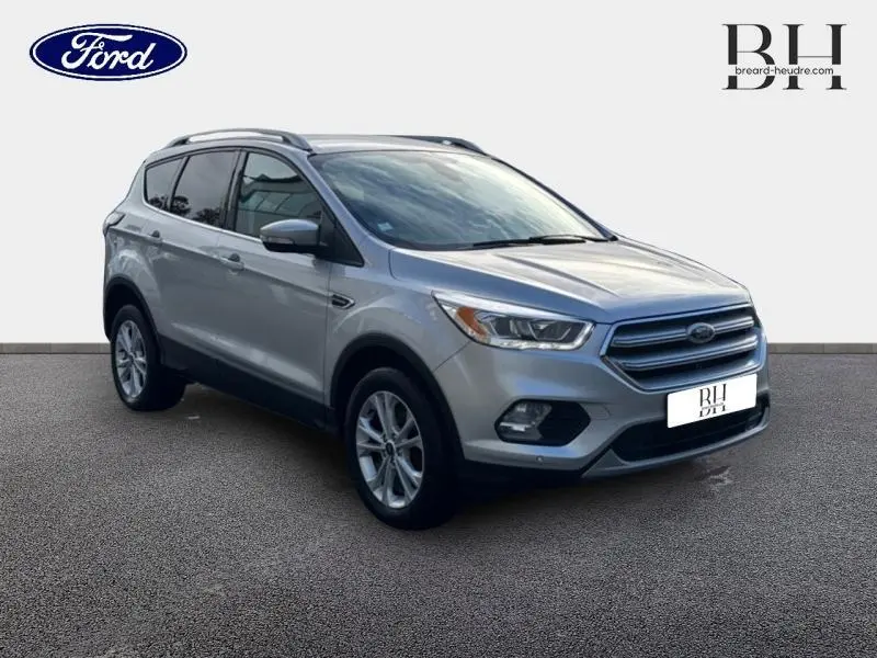 Ford Kuga gris lunaire vu en 3/4 avant droit, mettant en valeur ses jantes alu et ses lignes modernes.