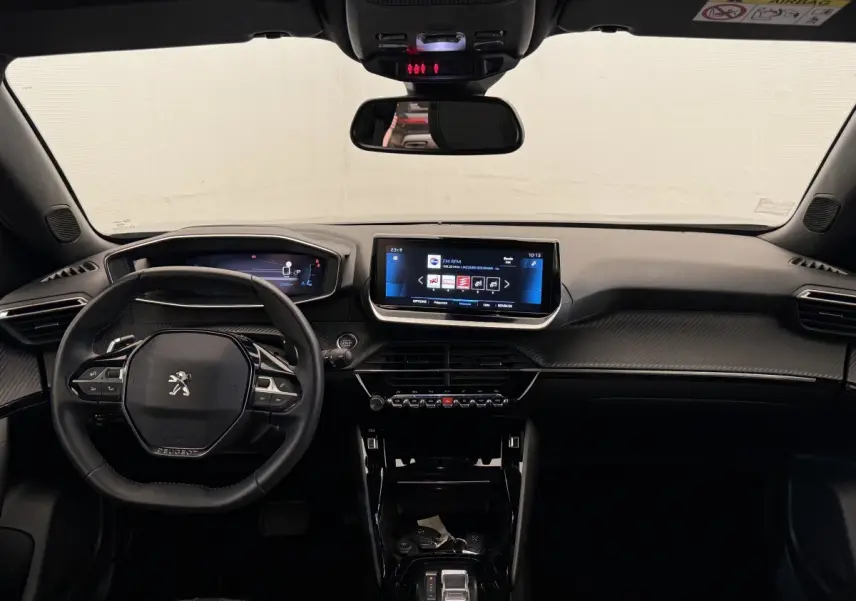 Vue intérieure frontale du tableau de bord noir du Peugeot 2008 2023 avec écran tactile central et volant multifonction cuir.