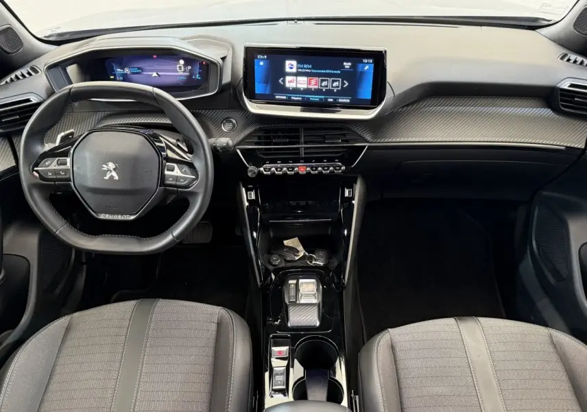 Vue intérieure avant du Peugeot 2008 2023, tableau de bord noir avec écran tactile central et volant compact cuir.