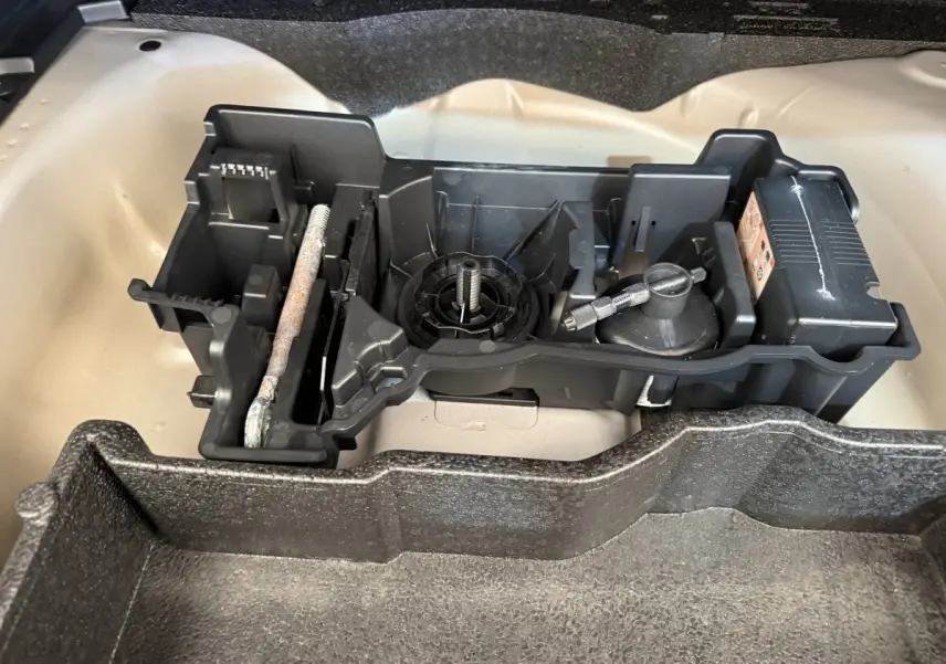 Gros plan sur le rangement d'outils dans le coffre beige d'un Peugeot 2008 gris clair, sans vue extérieure du véhicule.