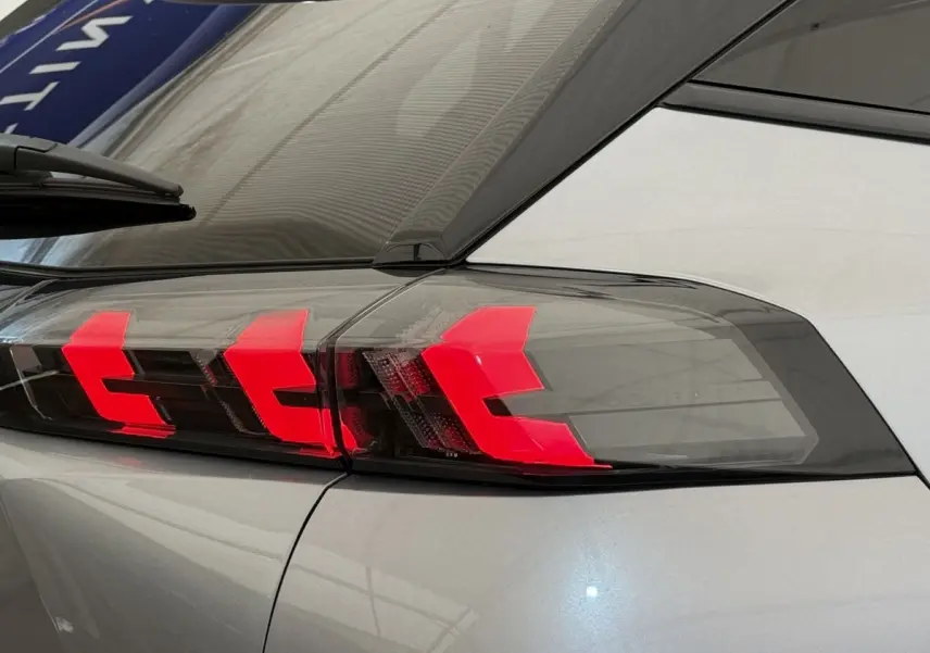 Gros plan sur le feu arrière droit rouge vif du Peugeot 2008 gris clair, soulignant le design moderne du SUV.