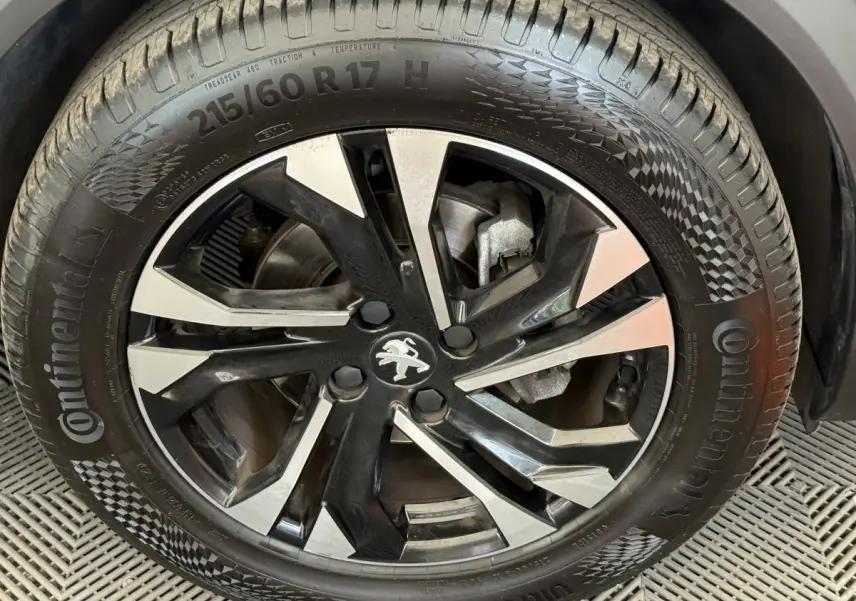 Gros plan sur la jante noire et argentée d’un Peugeot 2008 gris clair, mettant en valeur le logo lion central.