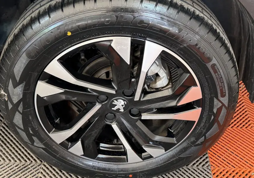 Vue rapprochée sur la roue avant droite d'un Peugeot 2008 gris clair, soulignant le pneu et la jante noire.