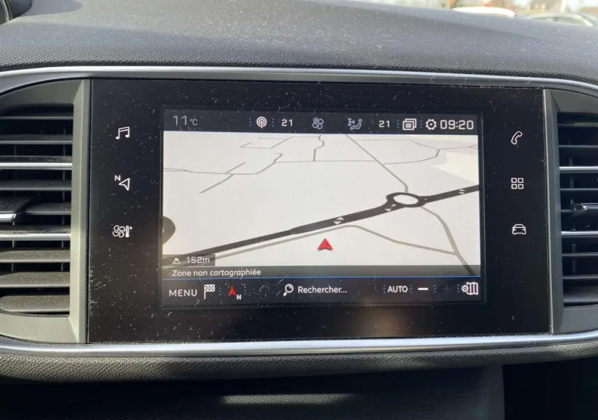 Écran tactile central du tableau de bord de la Peugeot 308 blanc nacré, affichant la navigation GPS en extérieur.