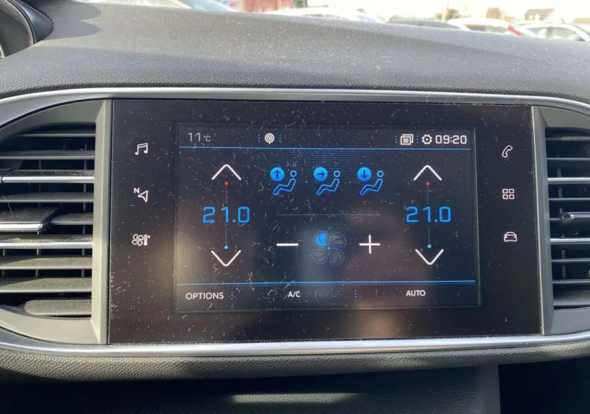 Écran tactile central de la Peugeot 308 blanc nacré de 2017 affichant la climatisation automatique bi-zone à 21°C.