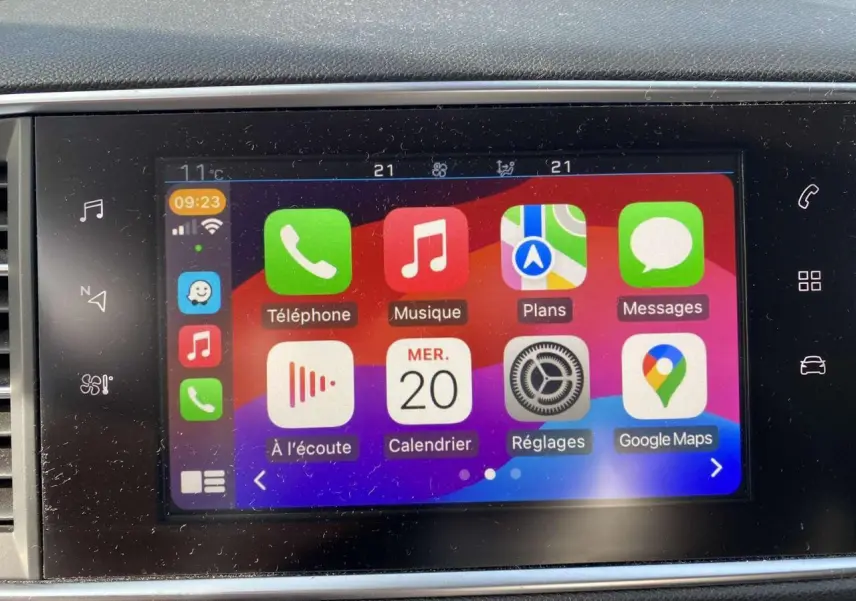 Écran tactile central de la Peugeot 308 blanc nacré, affichant l'interface Apple CarPlay avec applications colorées.