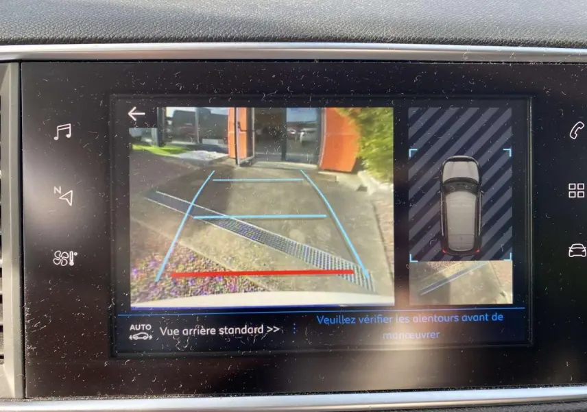Écran tactile montrant la caméra de recul et l'aide au stationnement arrière de la Peugeot 308 blanche nacrée.