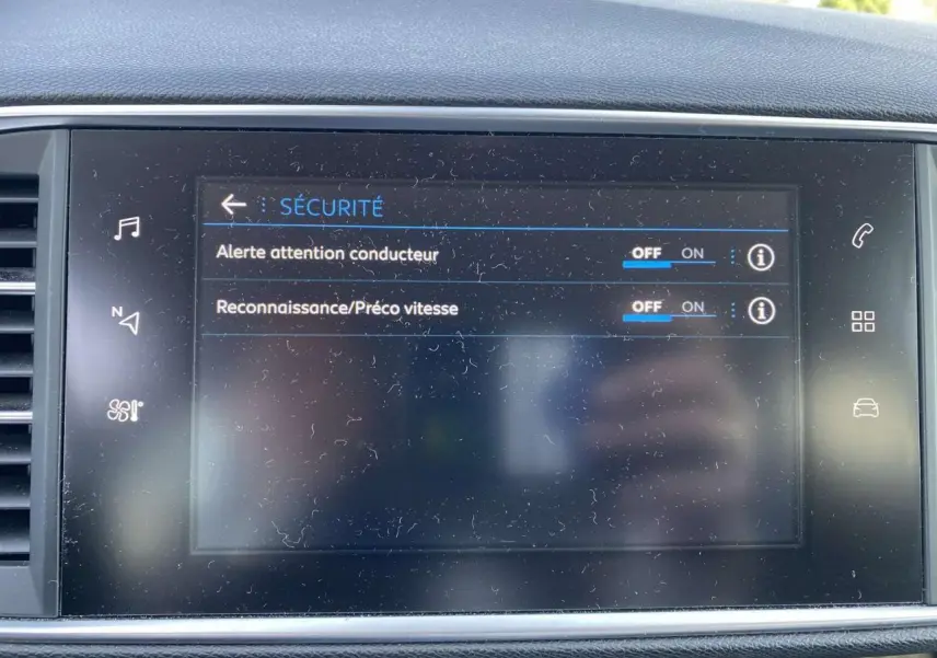 Écran tactile central de la Peugeot 308 blanc nacré montrant les réglages de sécurité du conducteur.