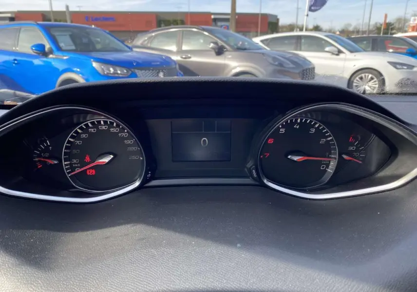 Vue rapprochée du tableau de bord de la Peugeot 308 blanche, affichant les compteurs à zéro en plein jour.